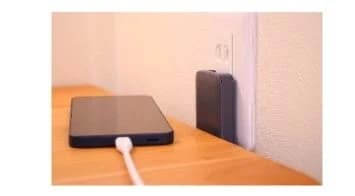 壁のコンセントに挿された充電器とスマートフォン