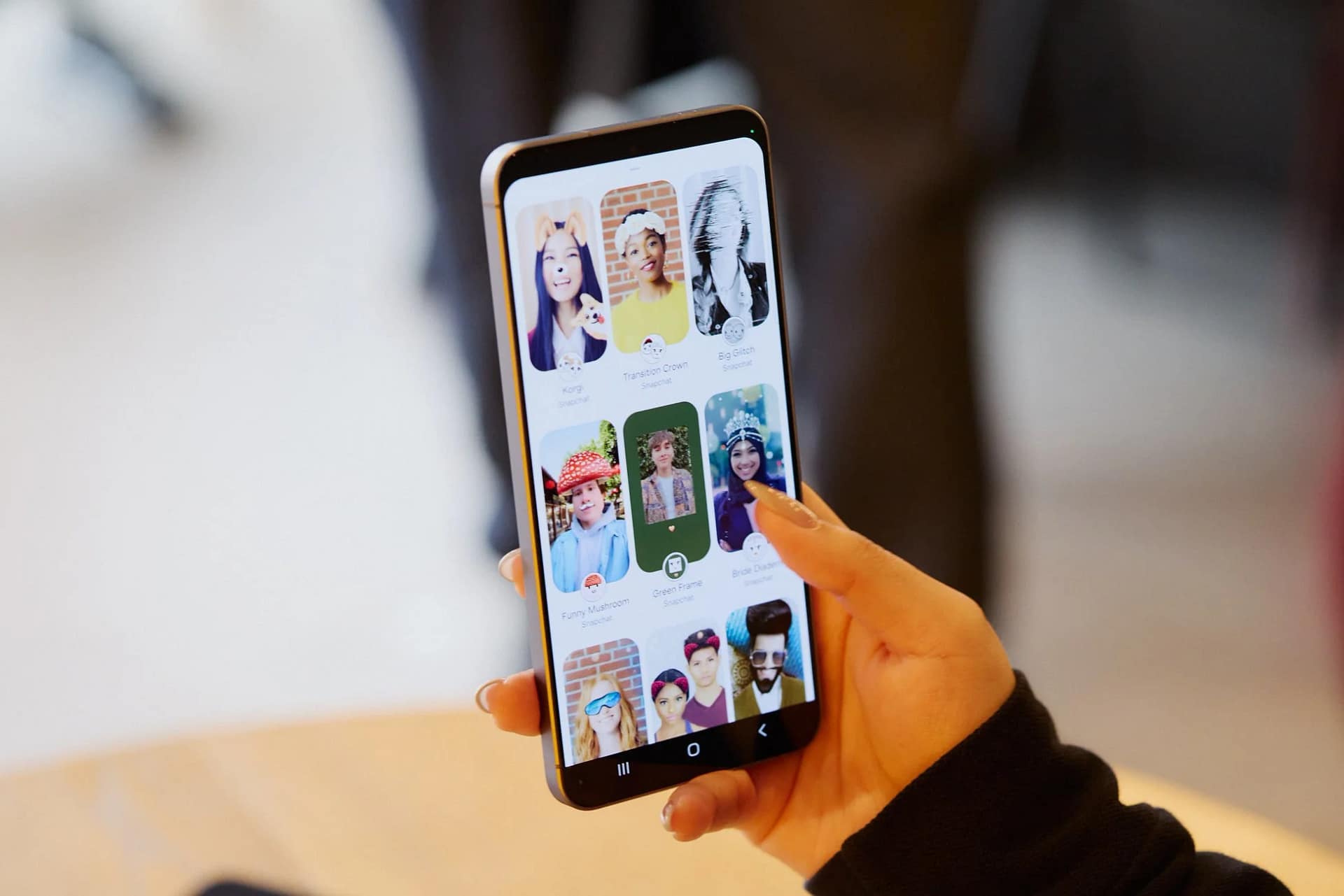 女性がスマートフォンを持ち、Snapchatアプリの様々なフィルターやレンズを閲覧している様子