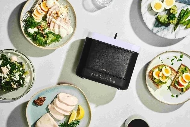 様々な卵料理、鶏肉、サラダなどが並べられた食卓の中央に、黒い調理器具が置かれています。